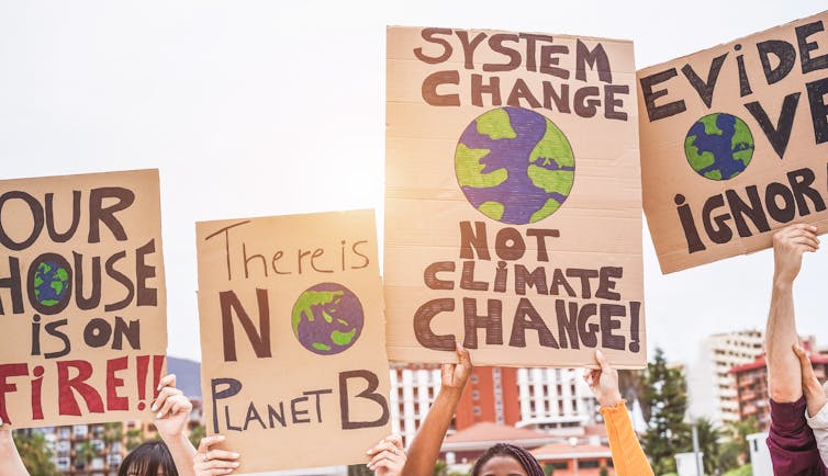 Climate activists carrying signs demanding action.