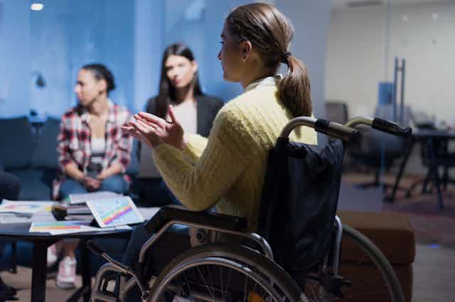 Woman in wheelchair talks to colleagues during a meeting