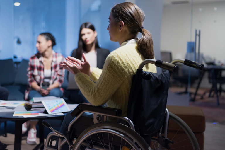 Woman in wheelchair talks to colleagues during a meeting