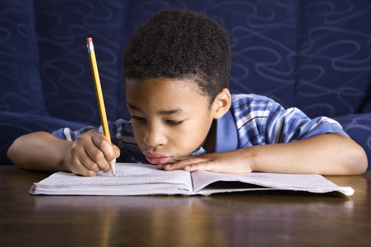 Boy writing with pencil in notebook