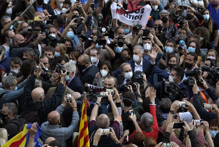 A man in a mask is surrounded by well-wishers in a crowd.