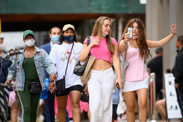 Girl takes selfie on phone while walking down a street