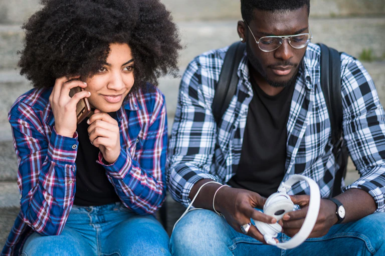 Two young black people sitting on some steps