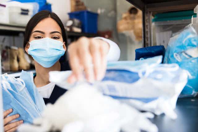 A woman picks up masks from a hospital supply room.
