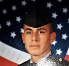 Soldier's headshot in uniform, against an American flag background