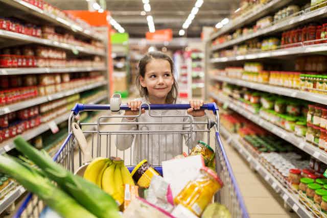 Girl with shopping trolley in supermarket.