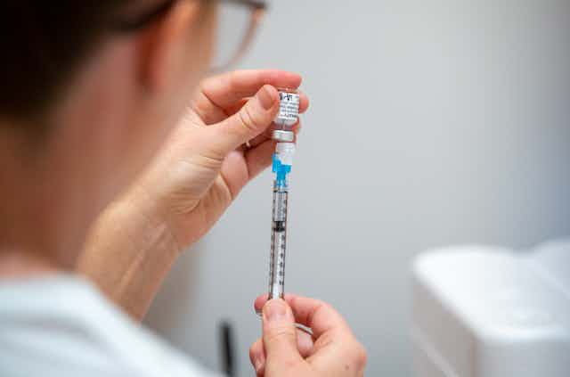 Health worker fills a syringe with vaccine
