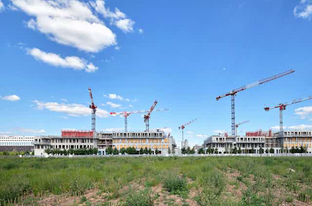 cranes tower over a large campus under construction