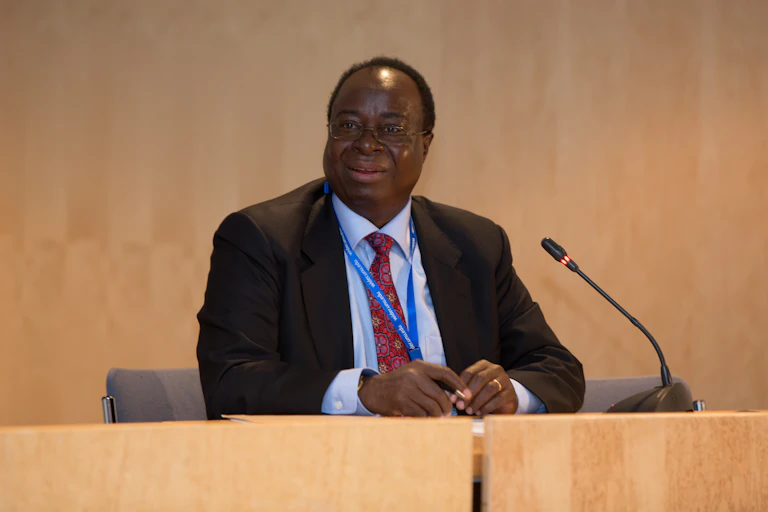 Man in a suit sitting in front of a microphone in a plenary