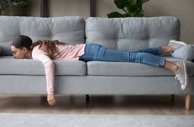 A girl lying on a sofa with her arm hanging down.