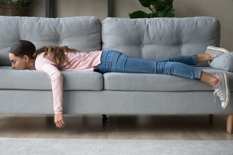 A girl lying on a sofa with her arm hanging down.