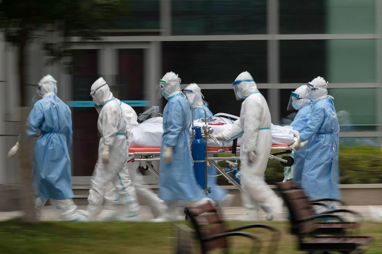 A COVID patient on a gurney surrounded by medics wearing PPE.