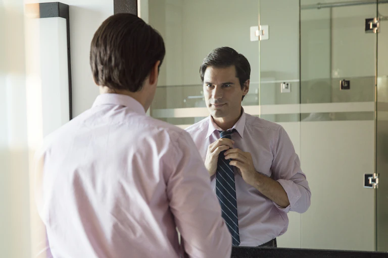 Man adjusting his tie in the mirror.