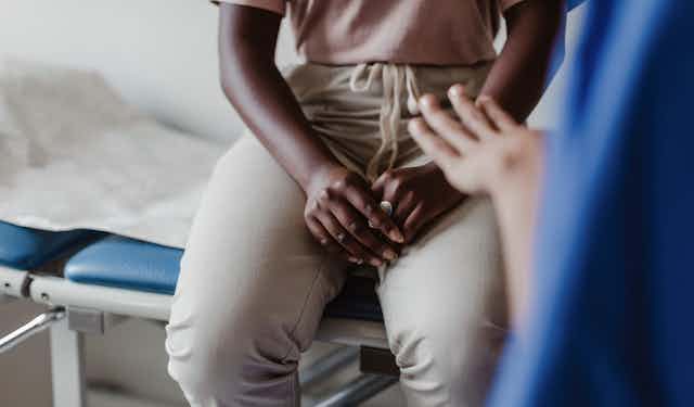 Hands of a Black woman seated on a medical exam table