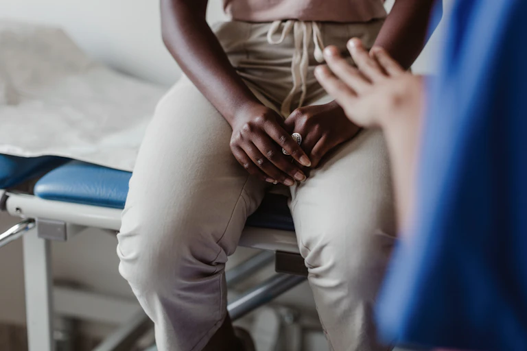 Hands of a Black woman seated on a medical exam table
