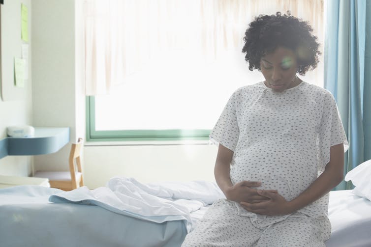 pregnant Black woman sits on hospital bed