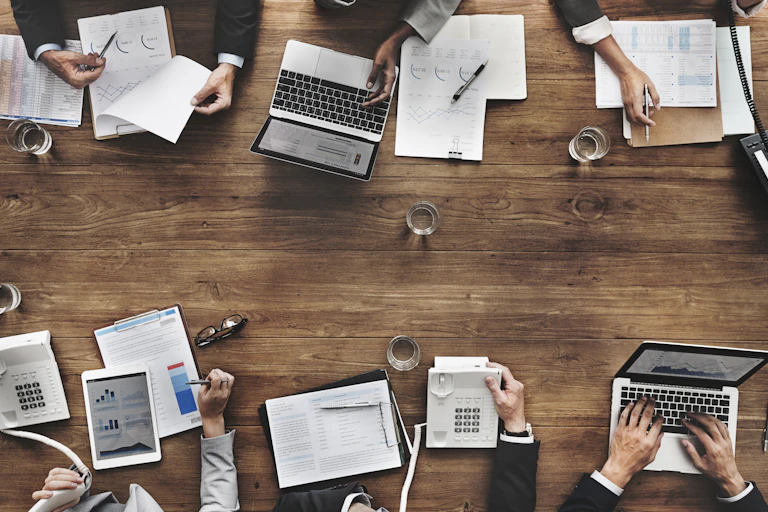 Photo of business meeting from above, hands, phones, documents