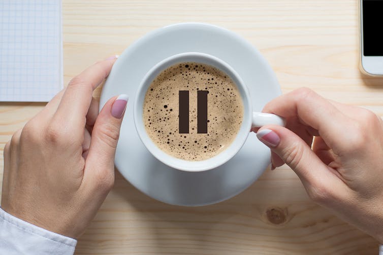 Overhead view of a cup of coffee with a 'pause' symbol in centre.