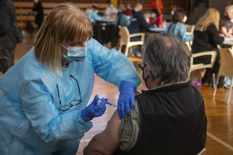 A healthare workers gives the coronavirus vaccine to and older man.