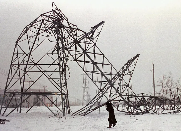 A transmission tower crumpled under the weight of ice.
