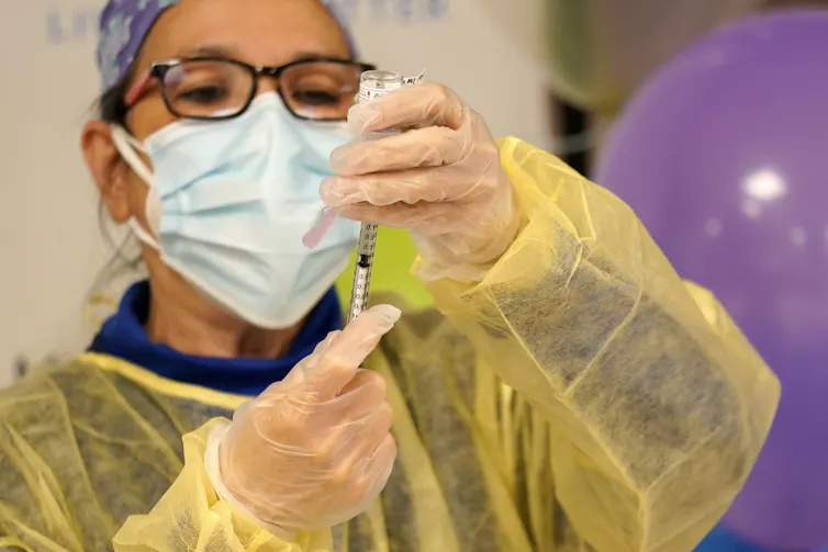 A nurse draws a dose of coronavirus vaccine into a syringe.