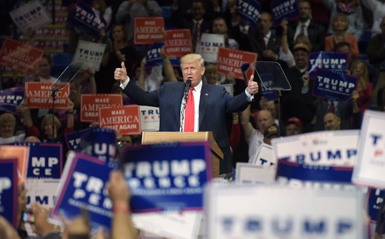Donald Trump at a rally with crowds and placards
