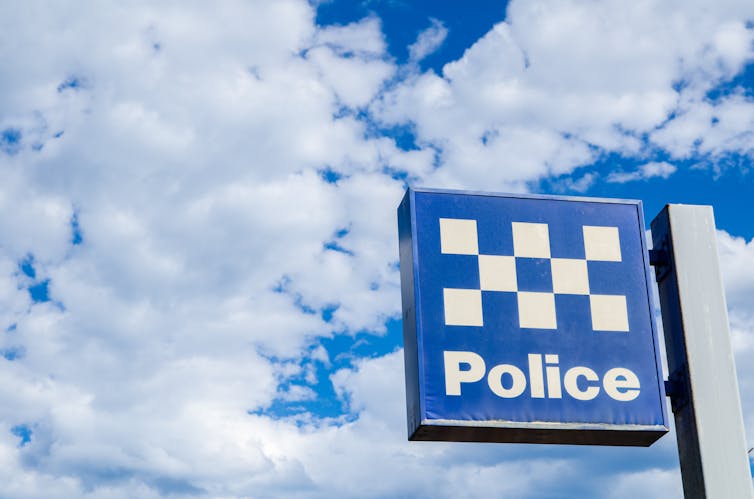 Police station sign against clouds and sky.