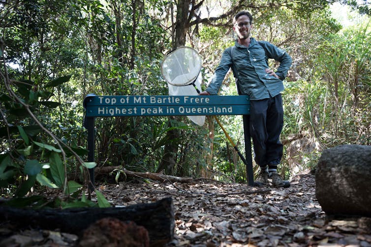 James poses with sign on Mt Bartle Frere