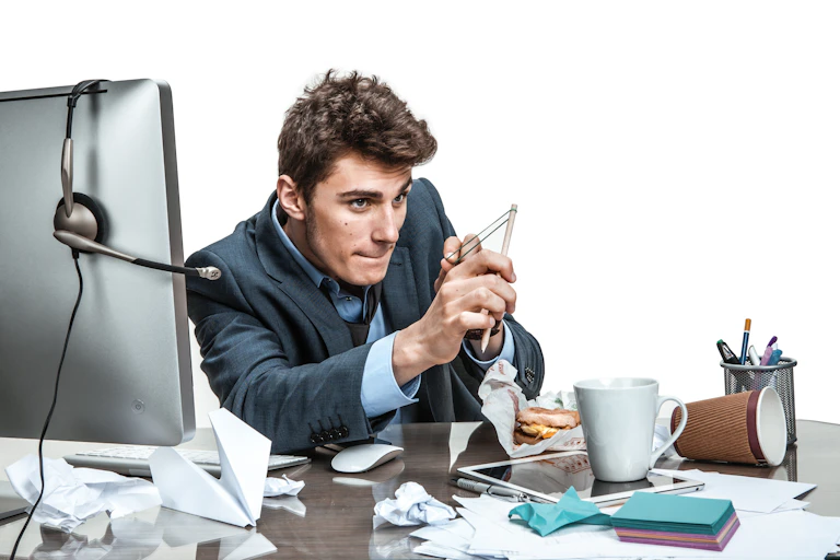 Man slacking off at work, making his pencil into a slingshot