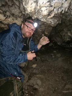 Axel Barlow with a cave bear bone deep inside a former hibernation cave.
