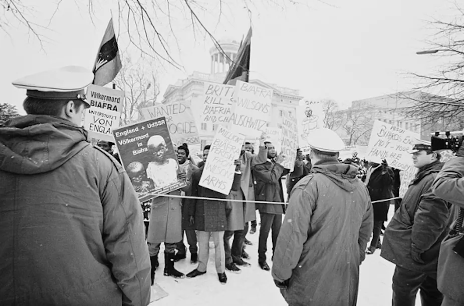 A group of people carrying placards and protesting before police officers.
