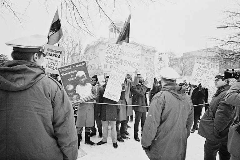 A group of people carrying placards and protesting before police officers.
