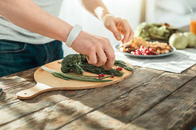 manos manipulando verduras en una tabla de cocina.