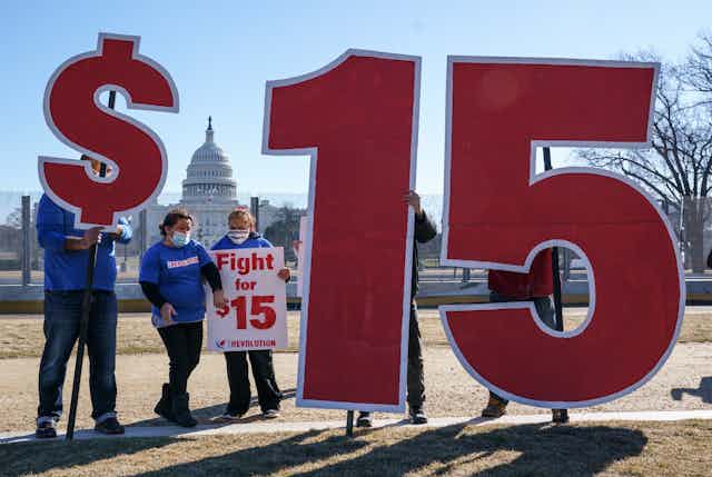Supporters of a $15 minimum wage had up signs, including a dollar sign and the numbers one and five, with the Capitol in the background