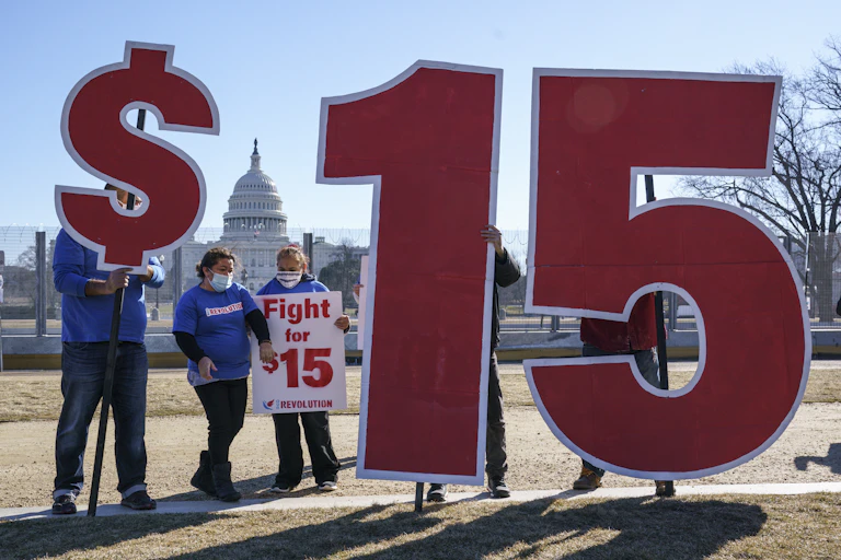 Supporters of a $15 minimum wage had up signs, including a dollar sign and the numbers one and five, with the Capitol in the background