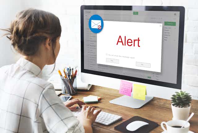 woman looking at laptop screen showing an email alert