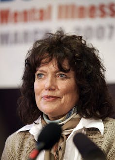 Margaret Trudeau at a microphone in front of a mental illness banner