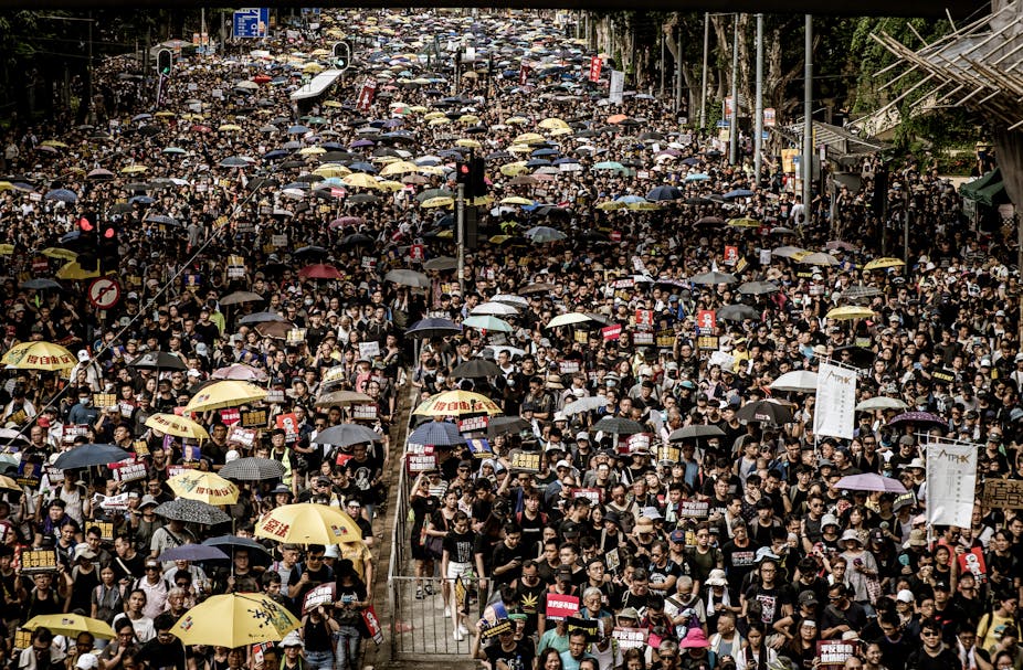 A large crowd of protesters, some holding umbrellas, on the streets of Hong Kong. 