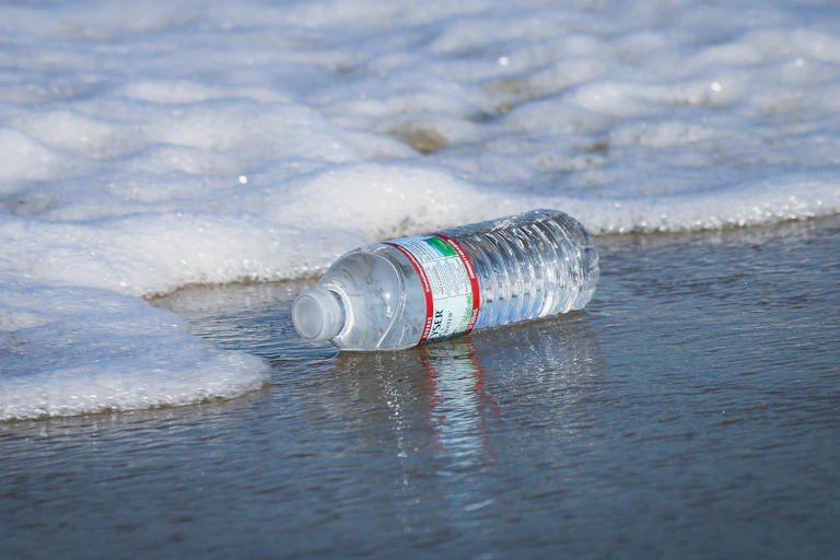 A plastic water bottle in the surf on a beach.