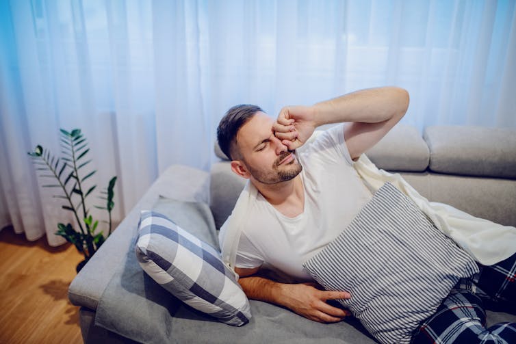 Man waking up from nap on the couch.