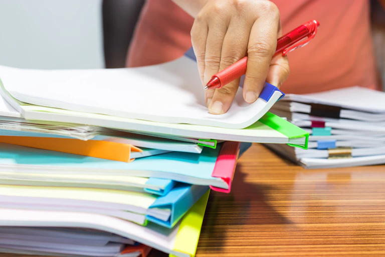 Hand with red pen and files