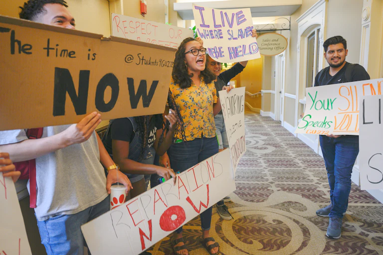 A group of students hold sign while protesting in the hallway.