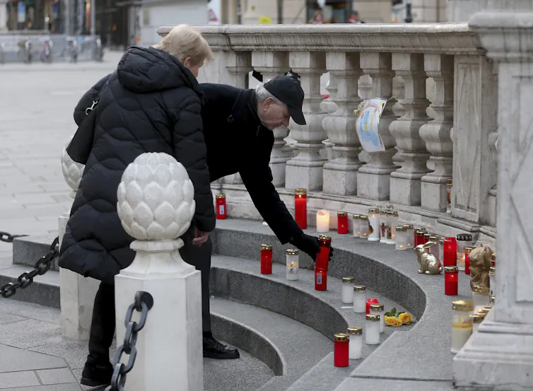 People light a candle at a plague column.