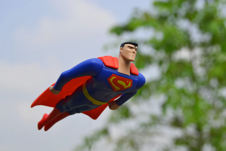 Toy Superman figurine flying past a tree.