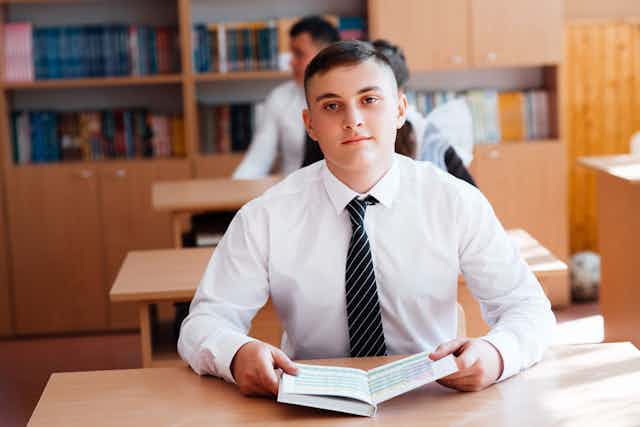 Boy at the desk with an open textbook in class
