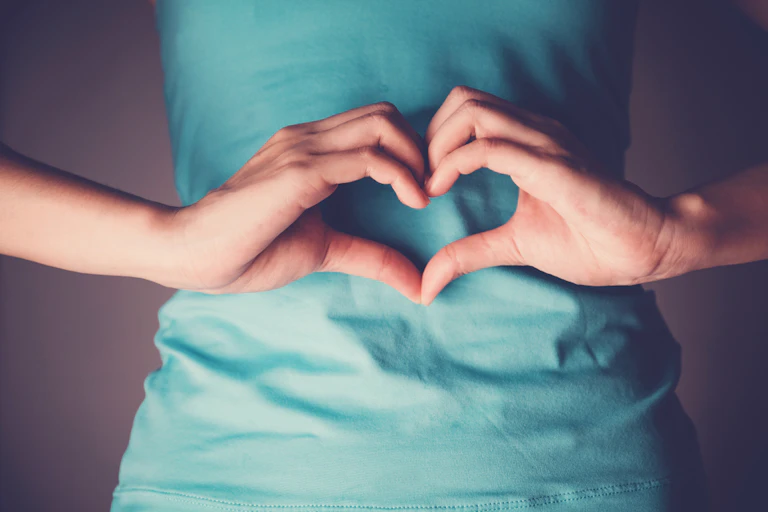 Hands making heart shape in front of tummy