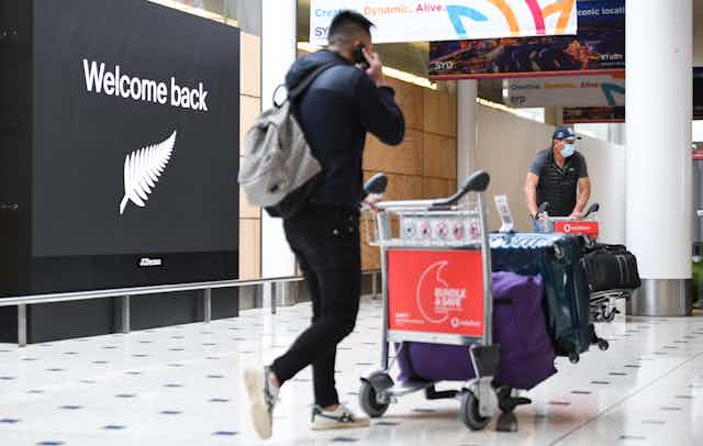 Passenger arriving at airport with welcome back sign in background