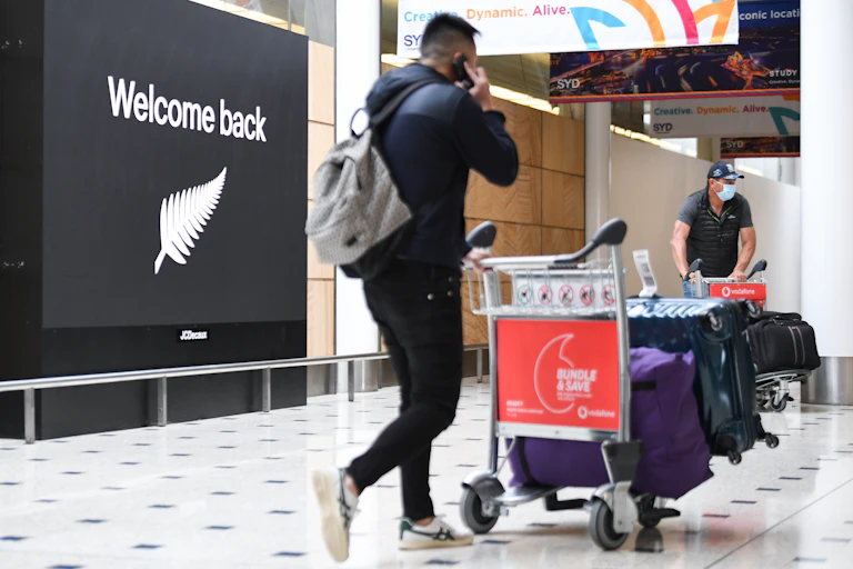 Passenger arriving at airport with welcome back sign in background