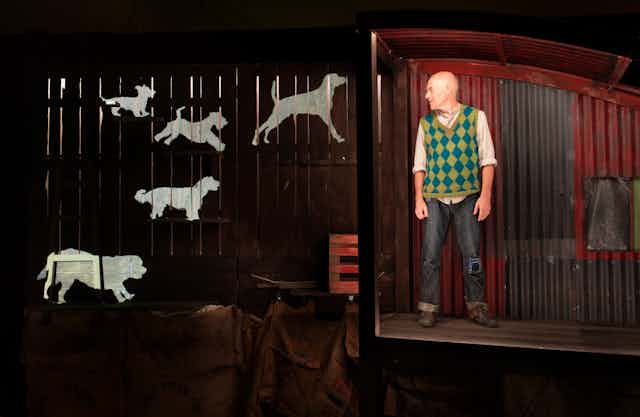 Production image – a man stands near projections of dogs