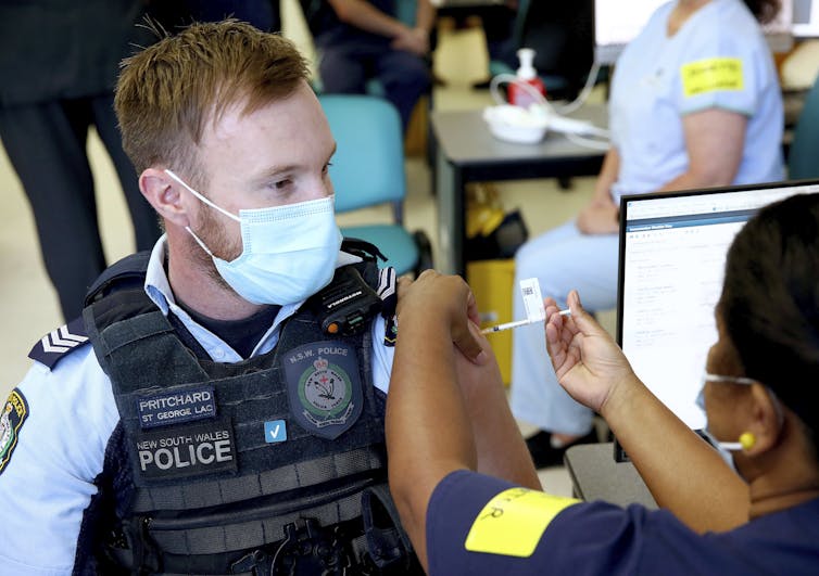 A young male police officer receives the vaccine in Sydney.